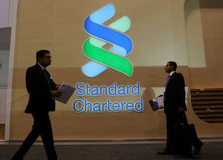 People pass by the logo of Standard Chartered plc at the SIBOS banking and financial conference in Toronto, Ontario, Canada October 19, 2017. REUTERS/Chris Helgren/Files