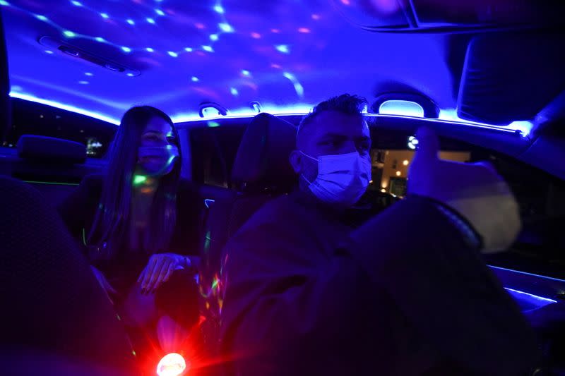 Greek driver Konstantinos Bekios, who has turned his taxi into a 'night club', gives a thumbs up to passenger Ioanna Karagiannidou in Thessaloniki