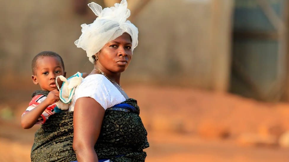 Una mujer en África carga su hijo en la espalda.
