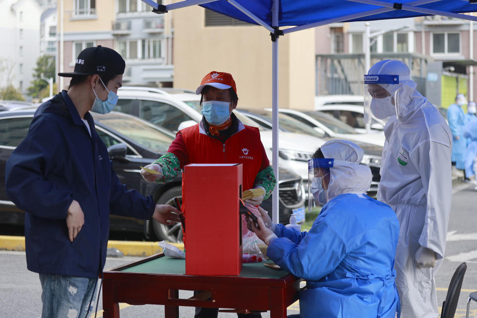 A resident prepares to get a COVID-19 tests at a residential community under lock down in Shanghai, China, Wednesday, March 30, 2022. As millions of Shanghai residents line up for coronavirus tests in the closed-down metropolis, authorities are promising tax cuts for shopkeepers and to keep its busy port functioning to limit disruptions to industry and trade. (AP Photo)