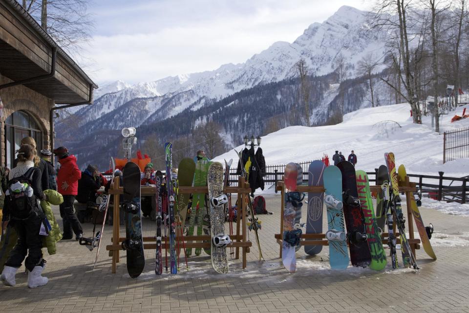 FILE - In this Wednesday, Feb. 6, 2013, file photo, snowboarders and skiers rest after competitions, in Rosa Khutor, some 60 km east of the Black Sea resort of Sochi, Russia. For visitors to the Winter Olympics, Sochi may feel like a landscape from a dream _ familiar and strange at once. Palm trees evoke a tropical seaside resort, but the Black Sea itself is seriously cold; turn away from the palms and the jagged, snow-covered peaks of the Caucasus Mountains rise nearby. (AP Photo/Ivan Sekretarev, file)