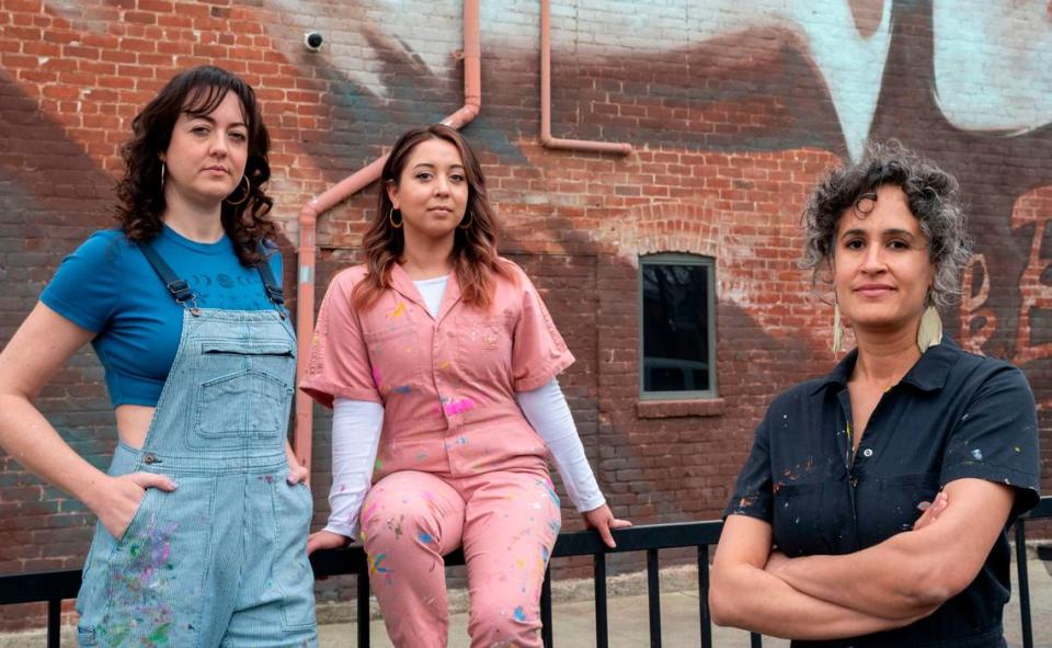 Sacramento artists, Jolene Rose Russell, left, Uli Smith, center and Jaya King stand in front of a mural March 22 on Oak Park’s Guild Theater done for Wide Open Walls in 2018. They claim the organization exploits new artists by underpaying them. Lezlie Sterling/lsterling@sacbee.com