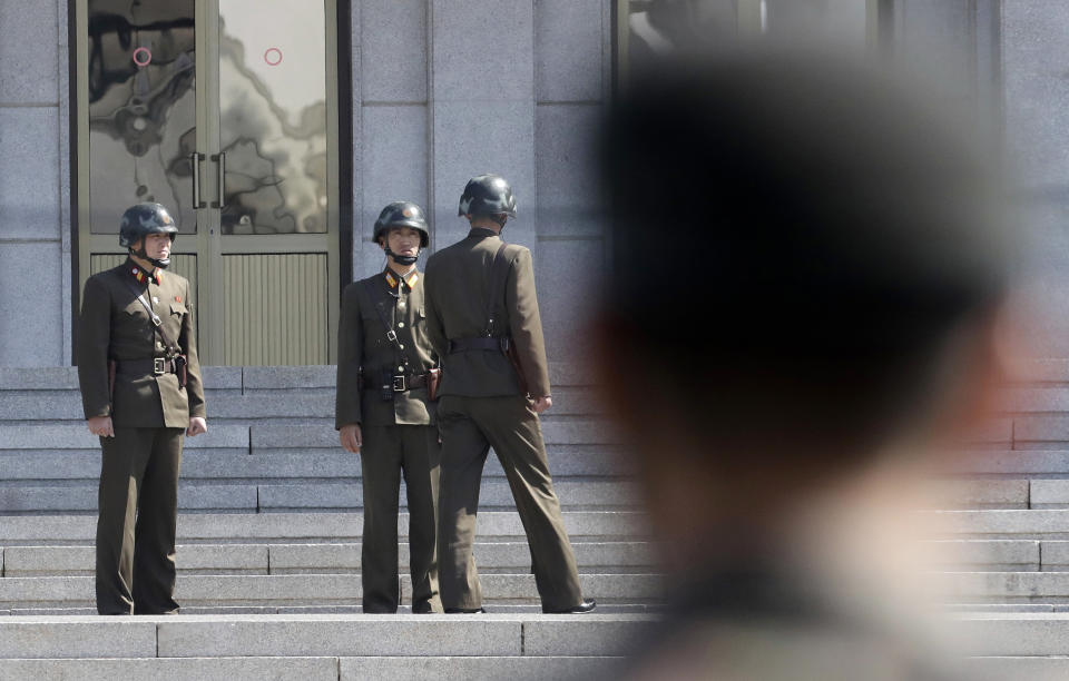 FILE - In this April 18, 2018 file photo, three North Korean soldiers talk each others as a South Korean soldier, right, stands at the border village of Panmunjom in the Demilitarized Zone, South Korea. North and South Korea began removing mines at two sites inside their heavily fortified border Monday, Oct. 1, 2018, as part of their recent deals to ease decades-long military tensions. The mine removal took place at the Koreas’ Joint Security Area in their shared border village of Panmunjom and another front-line area where the two countries plan their first joint searches for the remains of soldiers killed during the 1950-53 Korean War.(AP Photo/Lee Jin-man, File)