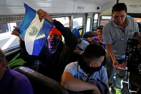 People in a caravan of migrants departing from El Salvador en route to the United States sit on a bus, in San Salvador, El Salvador, November 18, 2018. REUTERS/Jose Cabezas