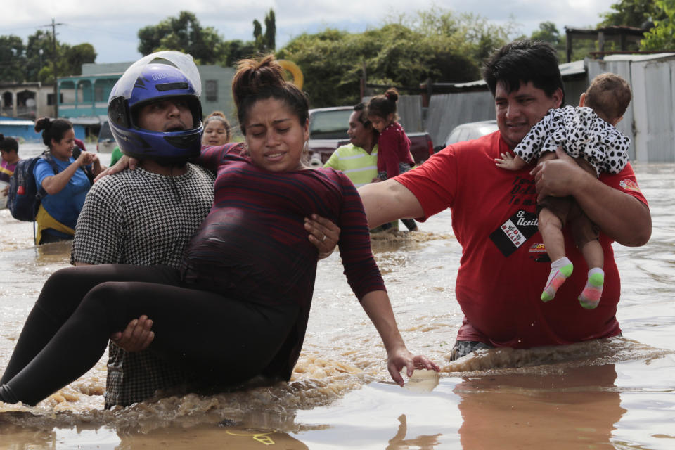 FILE - In this Nov. 5, 2020 file photo, a pregnant woman is carried out of an area flooded by water brought by Hurricane Eta in Planeta, Honduras. Thousands of homes were damaged and the infamous gang violence has not relented in Honduras, where some residents said gangs were charging a tax to boats trying to rescue people from flooded neighborhoods. (AP Photo/Delmer Martinez, File)