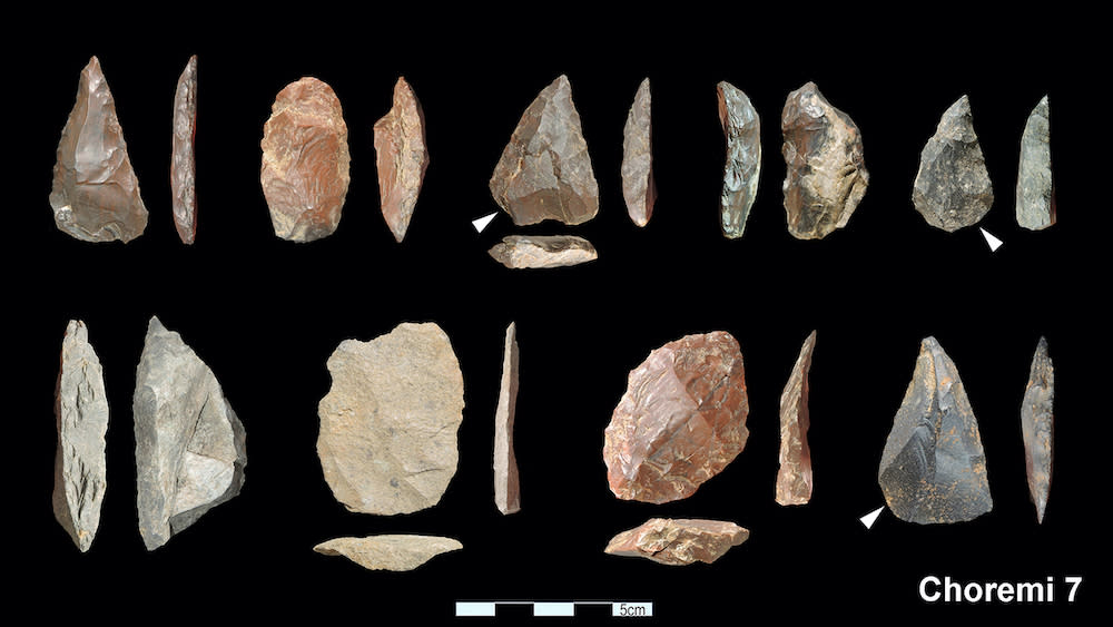  An array of stone tools against a black background. 