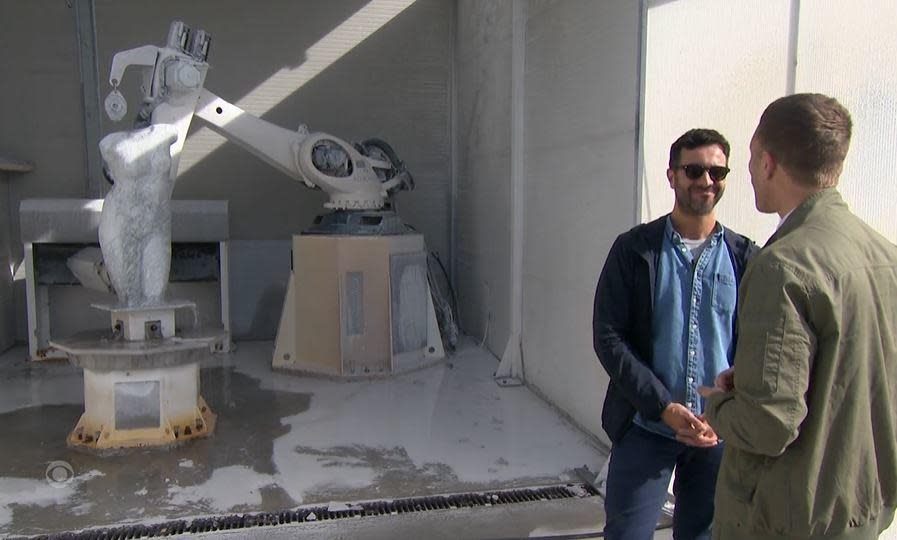 Robotor owner                  Giacomo Massari, left, speaks with CBS News' Chris Livesay at the company's facility in Carrara, Italy, as the 1L robot sculpts a block of marble into a Venus figure in the background.  / Credit: CBS News