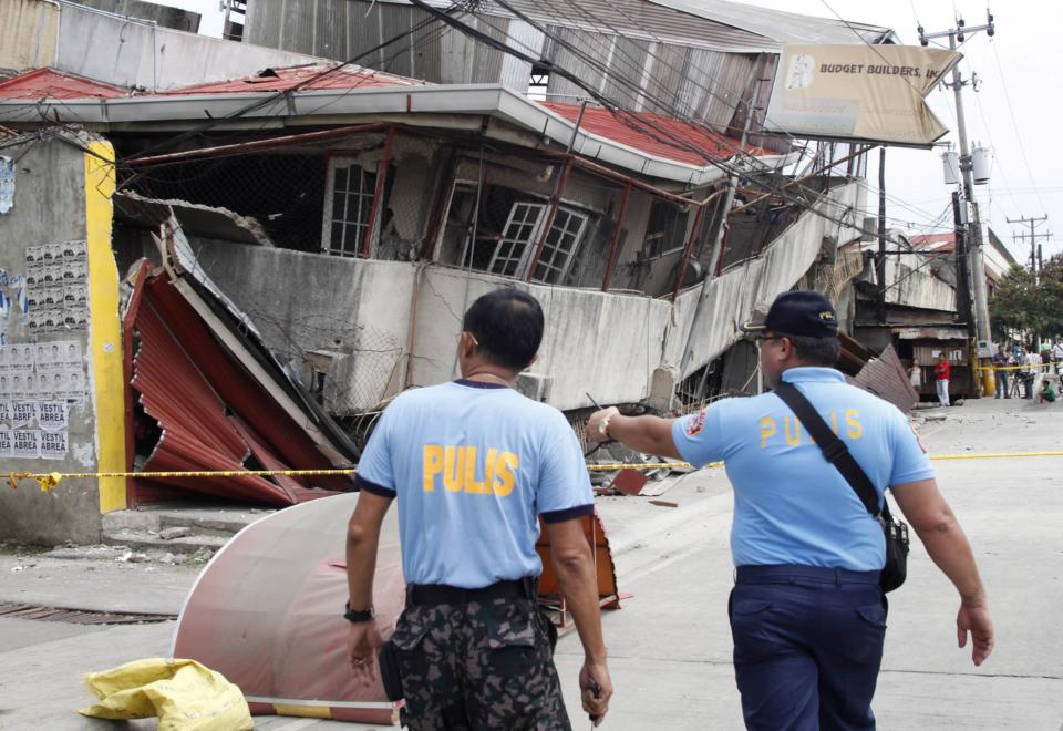 Police investigators inspect a collapsed building after an earthquake struck Cebu city, central Philippines October 15, 2013. At least six people were killed when buildings collapsed on islands popular with tourists in the central Philippines on Tuesday, radio reports said, after an earthquake measuring 7.2 hit the region. REUTERS/STRINGER (PHILIPPINES - Tags: DISASTER)