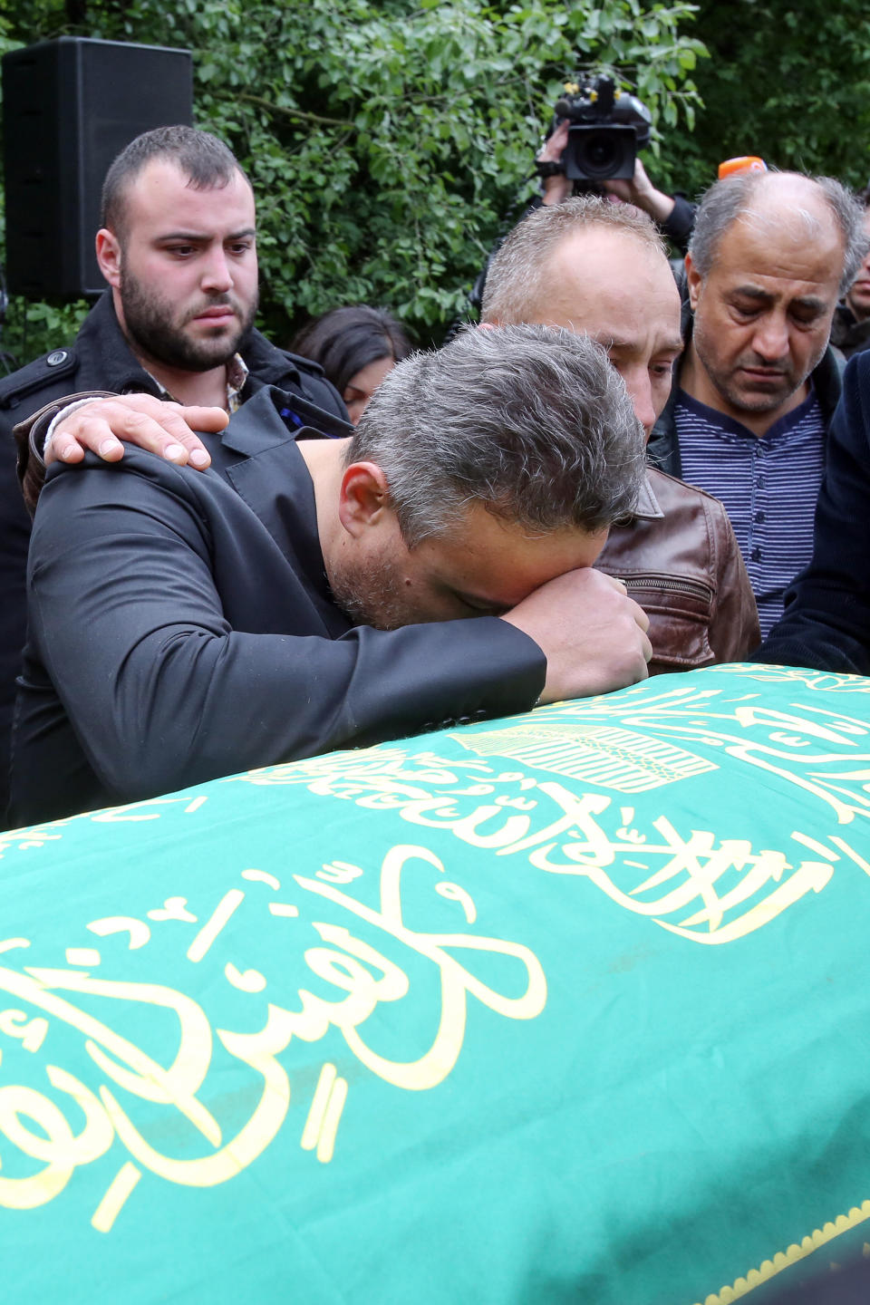 Celal Dede, front, mourns at the coffin of his son Diren during a funeral service in Hamburg, Germany, Sunday, May 4, 2014. More than 500 people were attending a memorial service for the 17-year-old German exchange student who was shot dead a week ago in the United States. (AP Photo/dpa, Bodo Marks)