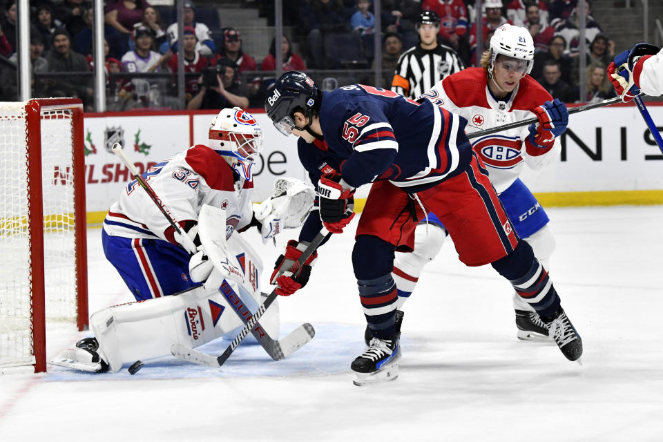 Montreal Canadiens goaltender Jake Allen (34) makes a save against Winnipeg Jets' Mark Scheifele (55) during the second period of NHL hockey game action in Winnipeg, Manitoba, Monday, Dec. 18, 2023. (Fred Greenslade/The Canadian Press via AP)