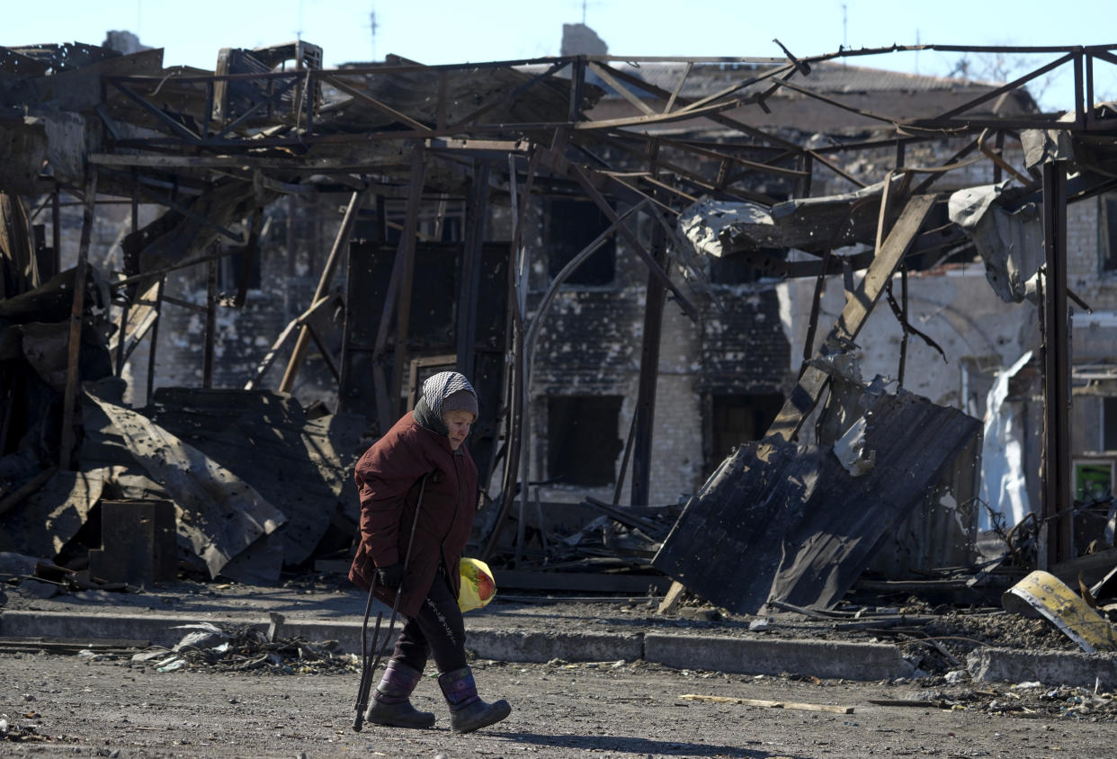 A woman walks past a destroyed building as civilians evacuate Mariupol, Ukraine.