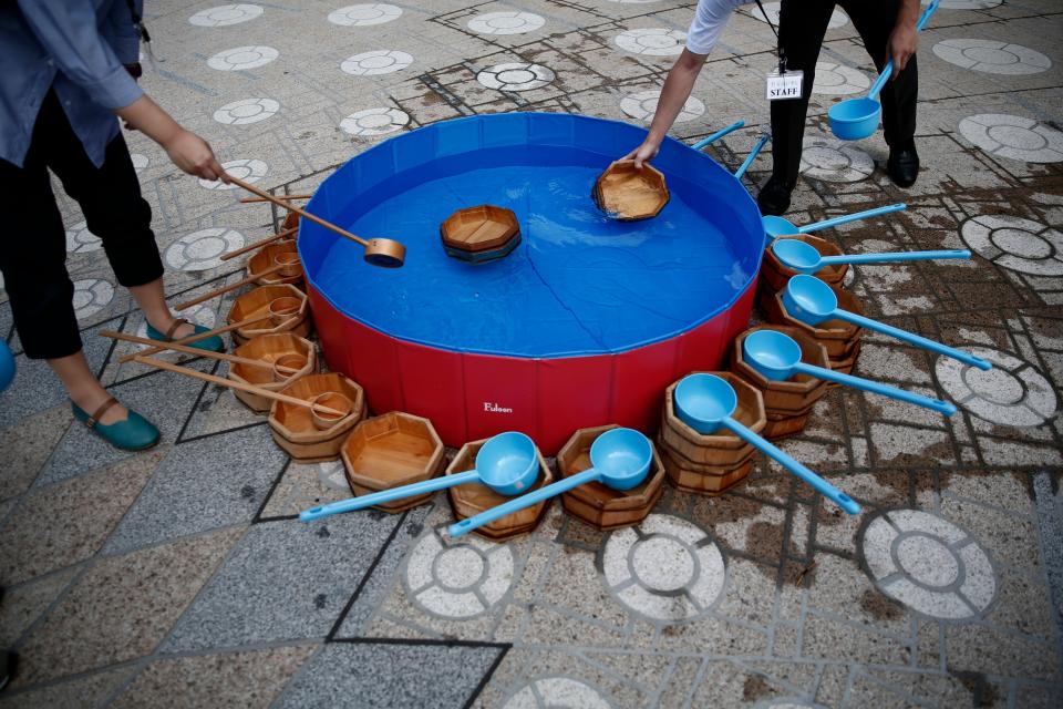 <p>People fill wooden buckets with water during a water sprinkling event called Uchimizu which is meant to cool down the area, in Tokyo on July 23, 2018. (Photo: Martin Bureau/AFP/Getty Images) </p>