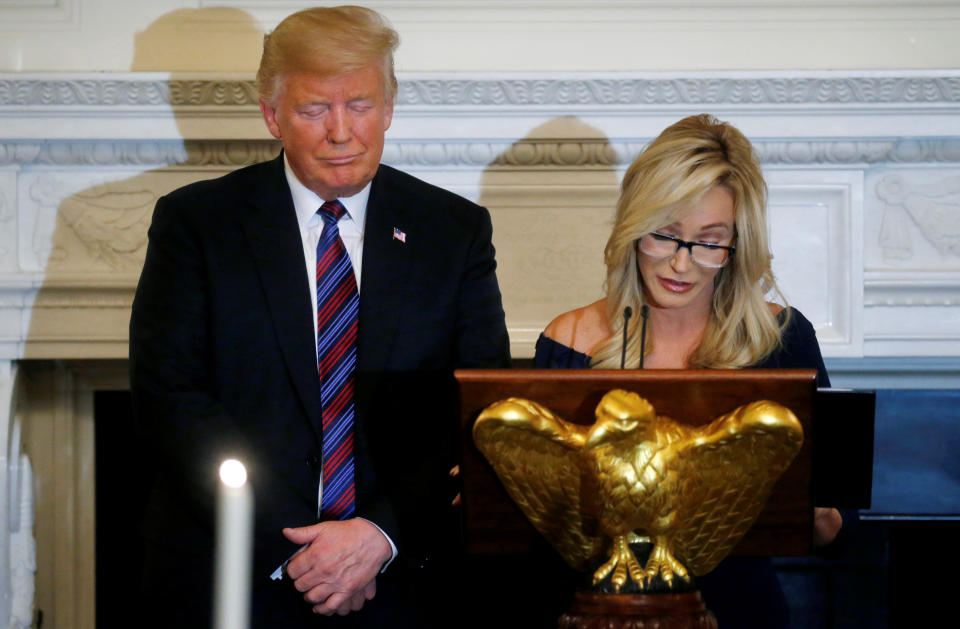 U.S. President Donald Trump closes his eyes as Pastor Paula White leads a prayer at a dinner hosted by the Trumps to honor evangelical leadership in the State Dining Room at the White House in Washington, D.C., U.S. August 27, 2018. REUTERS/Leah Millis