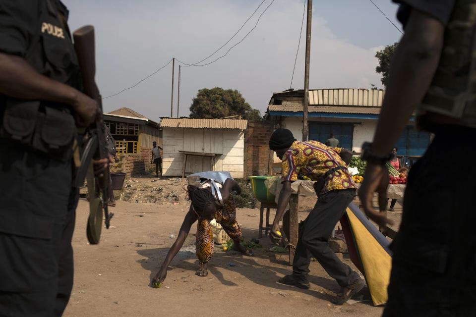 A man and a woman gather goods fallen from their road side kiosk shortly after AU peacekeeping soldiers dispersed a crowd on a street in Bangui