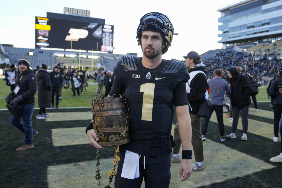 Purdue quarterback Hudson Card (1) carries the Old Oaken Bucket as he leaves the field after Purdue defeated Indiana in an NCAA college football game in West Lafayette, Ind., Saturday, Nov. 25, 2023. Purdue defeated Indiana 35-31. (AP Photo/Michael Conroy)