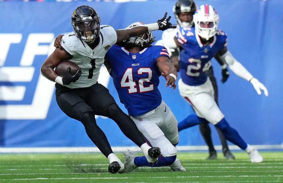 Jacksonville Jaguars running back Travis Etienne Jr. (1) holds off Buffalo Bills linebacker Dorian Williams (42) during an NFL football game between Jacksonville Jaguars and Buffalo Bills at the Tottenham Hotspur stadium in London, Sunday, Oct. 8, 2023. (AP Photo/Alastair Grant)