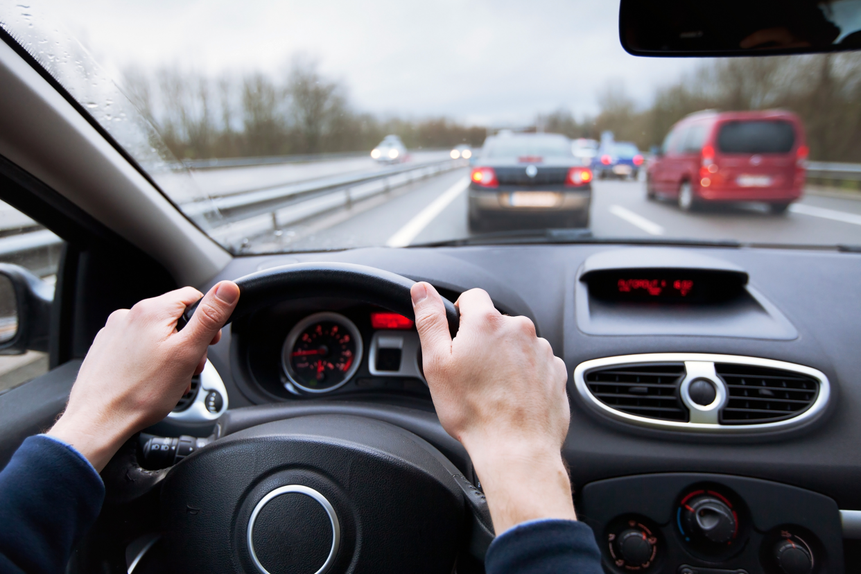 View of hands on steering wheel of car in traffic