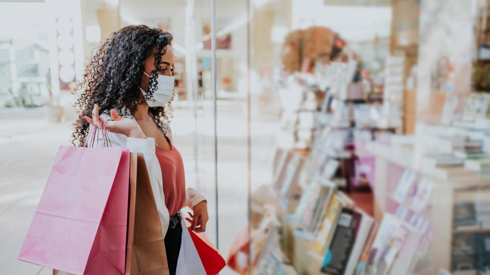 Woman in shopping mall with bags shopping during pandemic and wearing face mask against coronavirus.