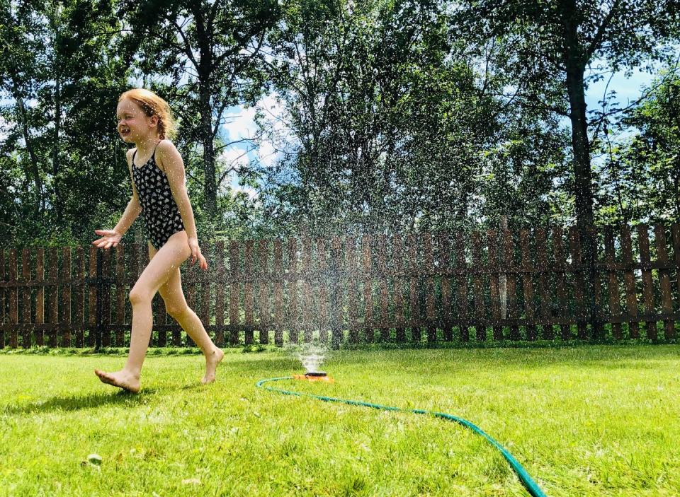 girl runs in sprinkler outside