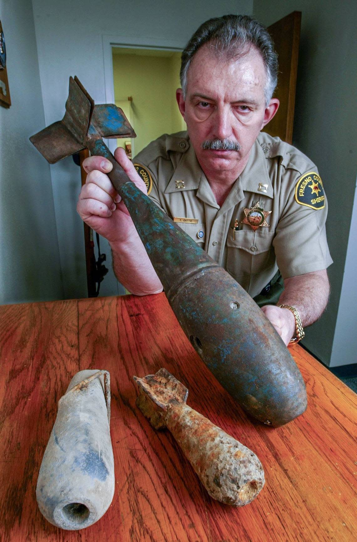FRESNO,CA 2-4-2004- MTD JRW WWII BOMBS - Fresno County Sheriff Department Captain Tom Gattie shows three World War II practice bombs which were unearthed in the Bonadelle Ranchos subdivision in Madera County, which was the site of a training bombing site for warplane drills (ck) during the war. The one at left, a 13-pound lead bomb, is the one most recently discovered by a man discing with a tractor, which cut off the tail fins. At middle is a 3-pound bomb, with the one at right that Gattie holds is a 25-pounder. (the one in middle and at right were found some years ago) JOHN WALKER/FRESNO BEE