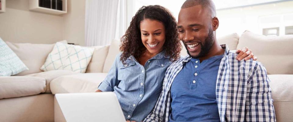 Young black couple using laptop sitting on the floor at home