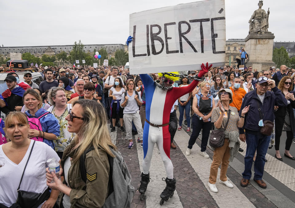 Anti-vaccine protester dressed in the colors of the French national flag holds a placard that reads liberty during a rally in Paris, Saturday, July 17, 2021. Tens of thousands of people protested across France on Saturday against the government's latest measures to curb rising COVID-19 infections and drive up vaccinations in the country. (AP Photo/Michel Euler)