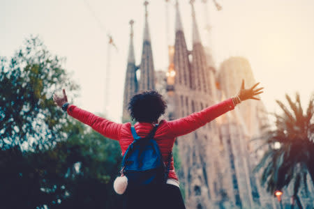 Rear view of young woman in front of Sagrada Familia with arms outstretched enjoying the beautiful city