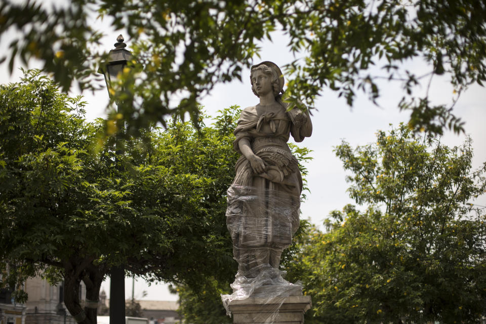 The bottom half of a sculpture of woman that represents autumn is wrapped in plastic, in Lima, Peru, Tuesday, Dec. 1, 2020. Monuments were practically spared, in part because they were protected with plastic or fabrics, but also because they were not the aim of protesters as they filled the streets, decrying a parliamentary coup in early November when Congress voted to oust ex-President Martín Vizcarra. (AP Photo/Rodrigo Abd)