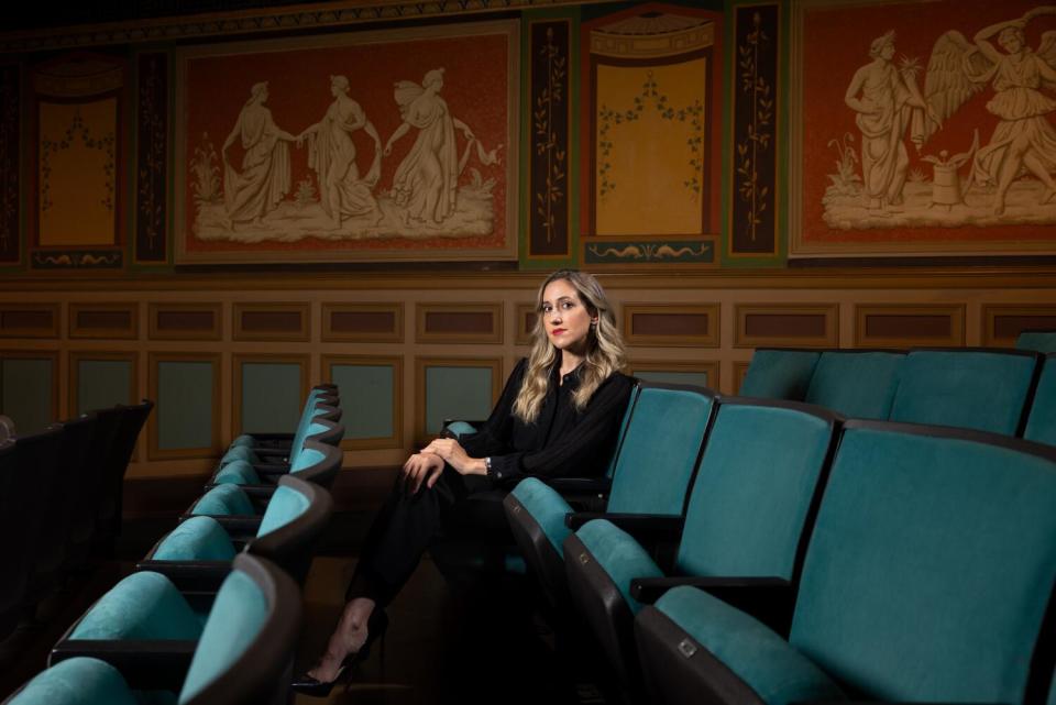 A woman sits in a theater.