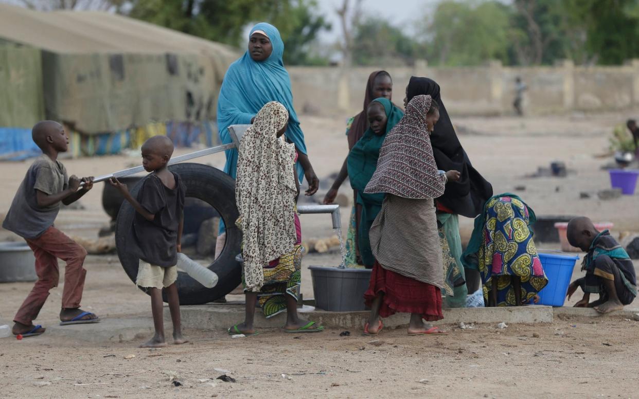 Women and children fetch water at a refugee camp in Yola, Nigeria - AP