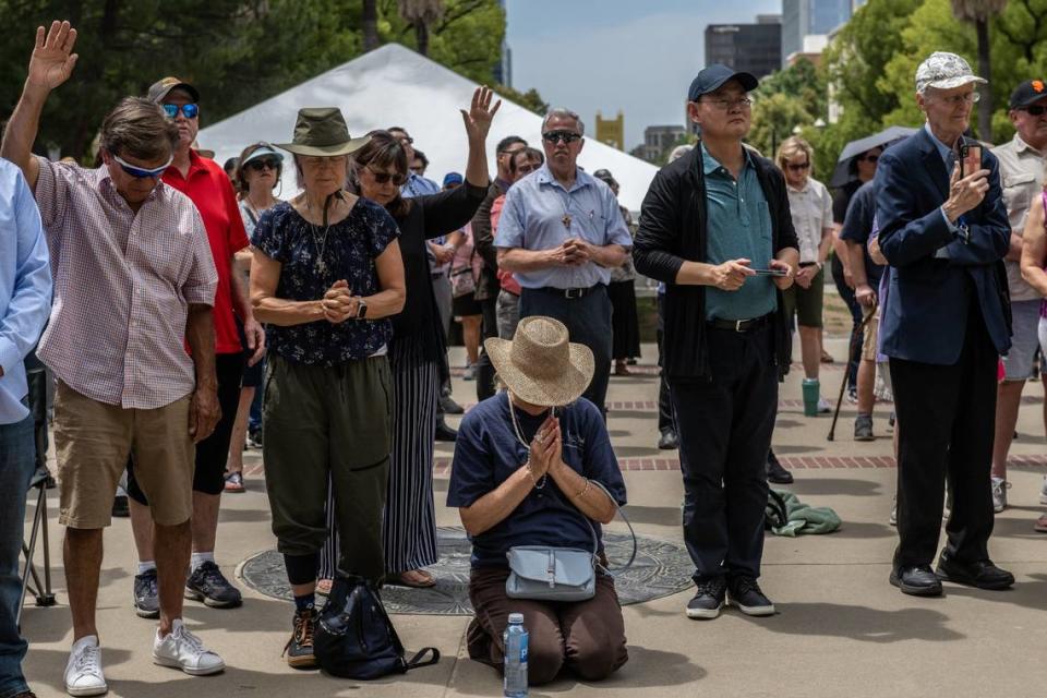 Marybeth Boumann, 58, center kneeling, is joined by her friend Elise Franck, 64, left, along with members of the California Family Council and the California Catholic Conference and others at a Christian prayer vigil outside the state Capitol on Monday, June 5, 2023. The event was in response to ceremonies on the Legislature honoring a member of the Sisters of Perpetual Indulgence for LGBTQ Pride Month. The religious groups accuse the drag nuns of mocking Christianity and Catholicism.