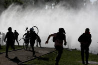Demonstrators run from tear gas launched by police as a state of emergency remains in effect in Santiago, Chile, Sunday, Oct. 20, 2019. Protests in the country have spilled over into a new day, even after President Sebastian Pinera cancelled the subway fare hike that prompted massive and violent demonstrations. (AP Photo/Esteban Felix)