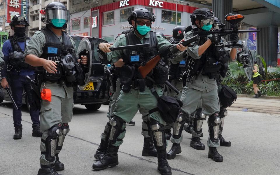 Hong Kong riot police fire tear gas as protesters march along a downtown street - AP