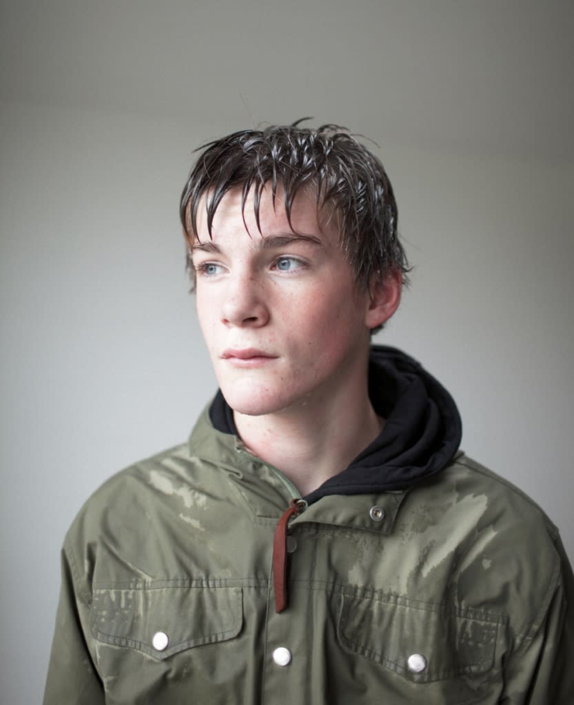 Portrait of teenage boy, right after coming in from the rain, with wet hair, face and coat.