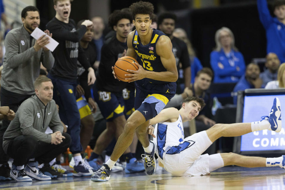 Marquette's Oso Ighodaro, left, carries the ball down court ahead of Creighton's Mason Miller during the first half of an NCAA college basketball game on Tuesday, Feb. 21, 2023, in Omaha, Neb. (AP Photo/Rebecca S. Gratz)