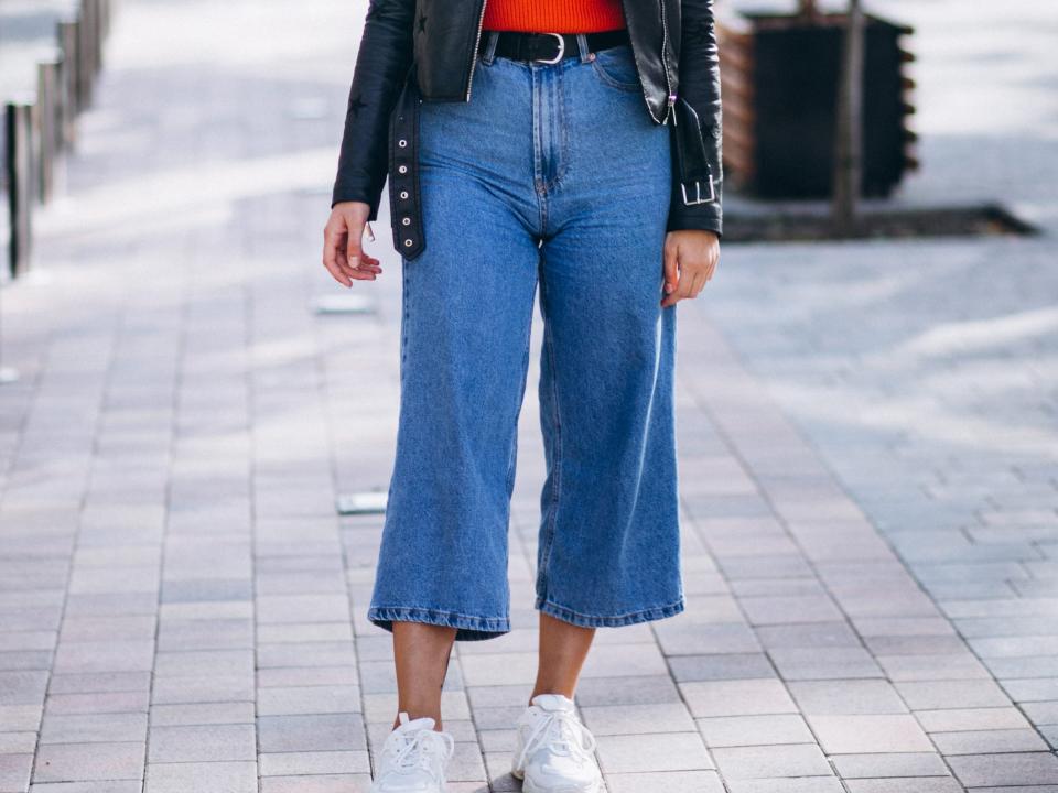 woman wearing wide-leg jeans, a sweater, and a leather jacket