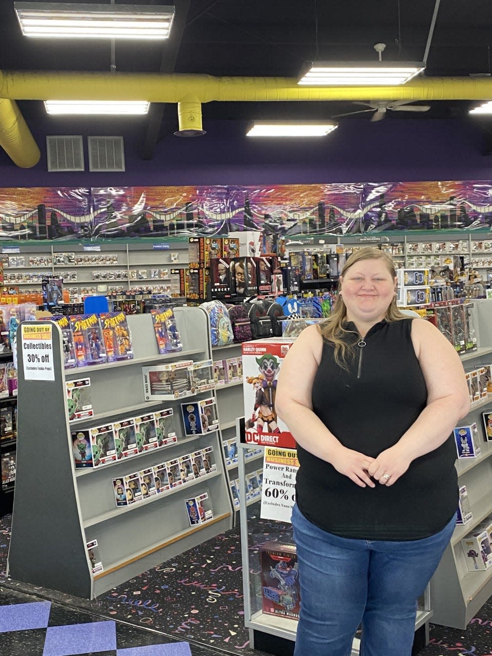 Movie Town employee Amy Smith stands in front of the collection. She has worked there for 12 years.