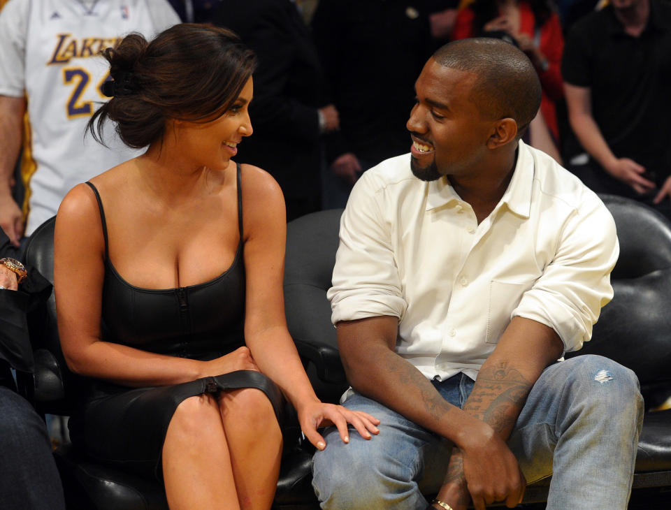 Kim Kardashian and Kanye West smiling at each other. 
