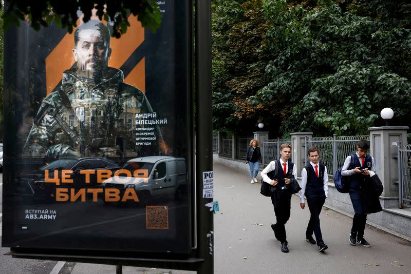 FILE PHOTO: School-aged boys walk past a poster calling on people to sign up for the army in Kyiv