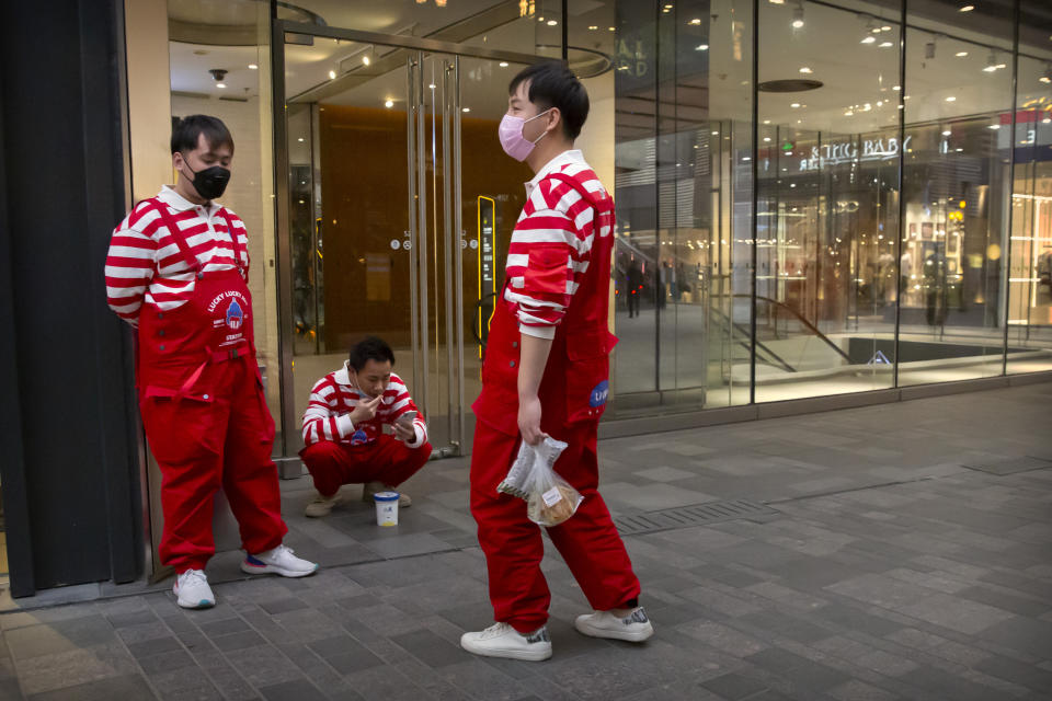 Retail workers wear face masks to protect against the spread of the new coronavirus as they take their break at an outdoor shopping area in Beijing, Friday, April 24, 2020. China reported no new virus deaths for the ninth straight day, and just six new cases on Friday. (AP Photo/Mark Schiefelbein)