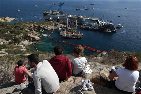 People look on as the capsized cruise liner Costa Concordia lies on its side next to Giglio Island September 16, 2013. REUTERS/Tony Gentile