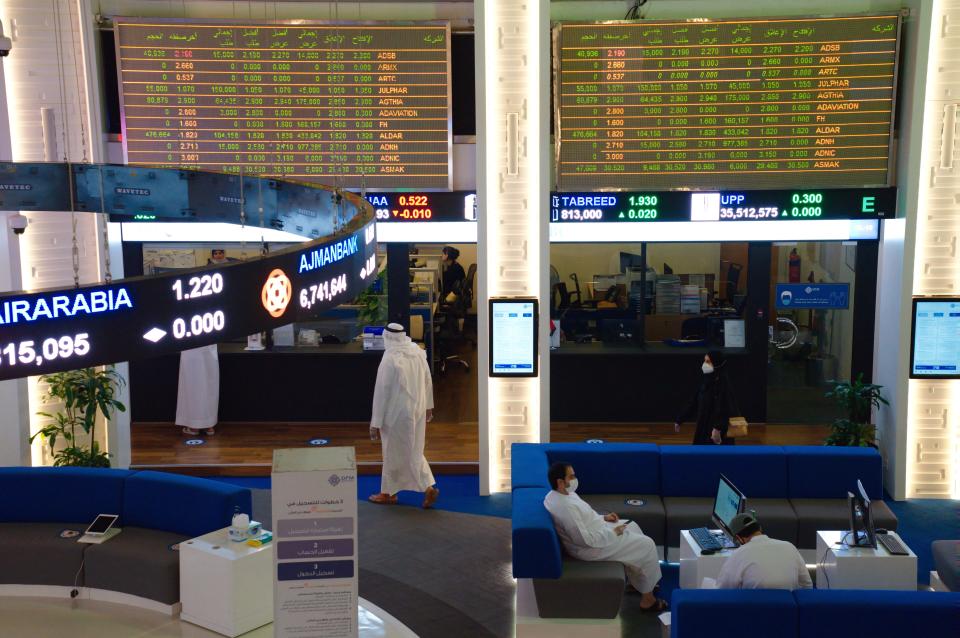 Emiratis wearing face masks due to the coronavirus pandemic work on the floor of the Dubai Financial Market in Dubai, United Arab Emirates, Tuesday, July 7, 2020. Dubai reopened its Dubai Financial Market stock exchange Tuesday after closing its floor due to the coronavirus pandemic. (AP Photo/Jon Gambrell)