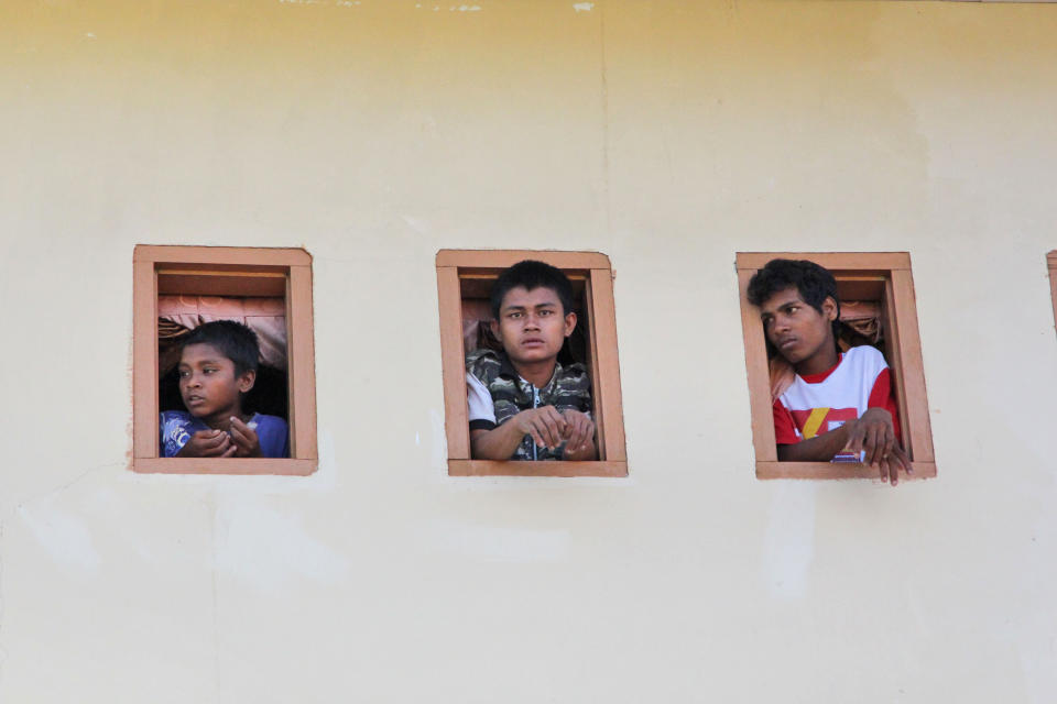 Ethnic Rohingya migrants look out of windows of a temporary shelter in Lhok Sukon, Aceh province, Indonesia, Monday, May 11, 2015. (AP Photo/S. Yulinnas)