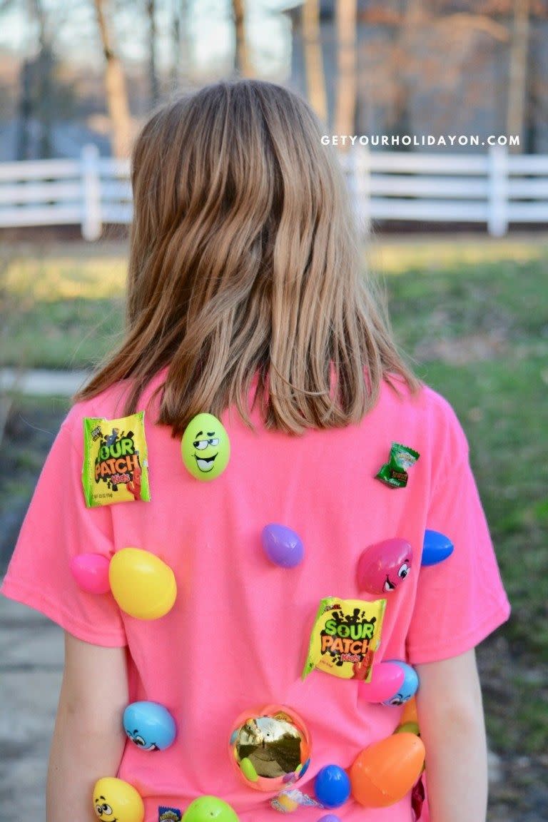 girl wearing pink shirt with plastic eggs and candy prizes attached to back for tag game alternative to easter egg hunt