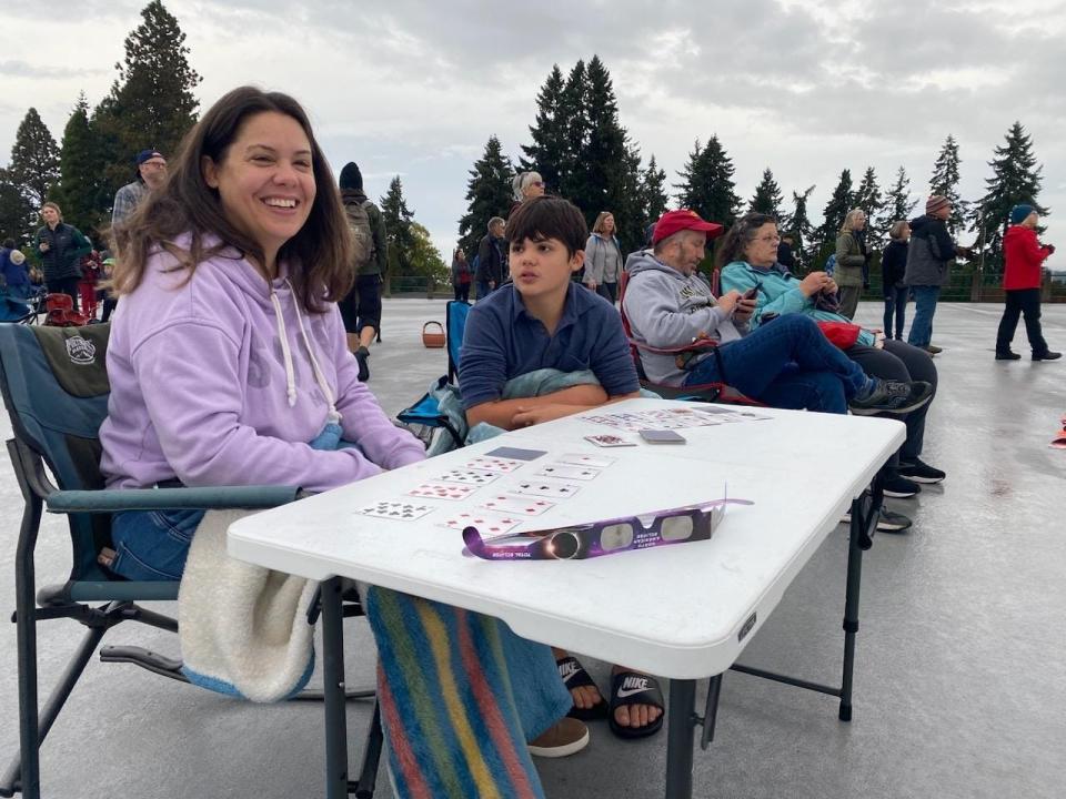 Dianne Garcia, left, and her family are hoping to get a glimpse of the eclipse Saturday morning at the College Hill Reservoir. “We’re sure hoping. We’re Jewish and it was something that could give us a break from the events of the week.” Garcia set up a table to play “Garbage” with her family while waiting for the eclipse to start.