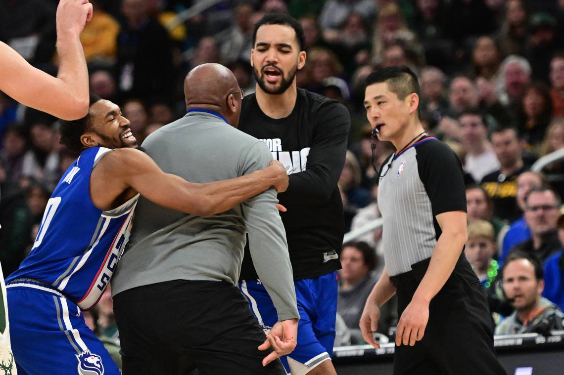 Sacramento Kings coach Mike Brown is restrained by guard Malik Monk (0) as he argues with referee Intae Hwang in the fourth quarter Sunday in Milwaukee. Benny Sieu/USA TODAY Sports