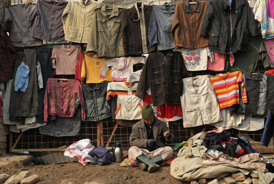 FILE - In this Jan. 14, 2014, file photo, an Afghan man selling secondhand clothes waits for customers in Kabul, Afghanistan. With millions of dollars in foreign aid flooding into the country, many Afghans still live in poverty. Uncertainty over how many U.S. troops might remain in Afghanistan beyond this year has trickled down to American diplomats and aid workers whose efforts over the last decade to develop the still mostly primitive country faces a drawdown of its own because of security fears. (AP Photo/Rahmat Gul, File)