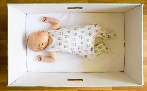 A baby asleep in the cardboard box that all new parents receive in Finland, which has one of the lowest infant mortality rates in the world - Credit:  Milla Kontkanen / Alamy Stock Photo