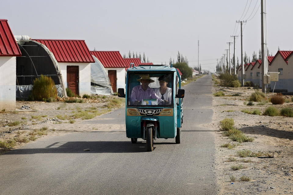 In this Sept. 21, 2018, photo, Han Chinese ride in a tricycle passing by farmhouses at the Unity New Village in Hotan, in western China's Xinjiang region. The Trump administration, locked in a trade war with China, is increasing the pressure on Beijing over what it says is the systematic oppression of ethnic minority Muslims. American officials hosted a panel Tuesday, Sept. 24, 2019, on the sidelines of the United Nations General Assembly gathering in New York to highlight the plight of Uighurs, whose native land in China’s far western Xinjiang province they say is a police state. (AP Photo/Andy Wong)