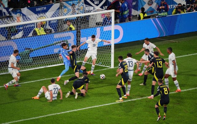 Switzerland players scramble to clear th eball as Scotland players crowd the six-yard box